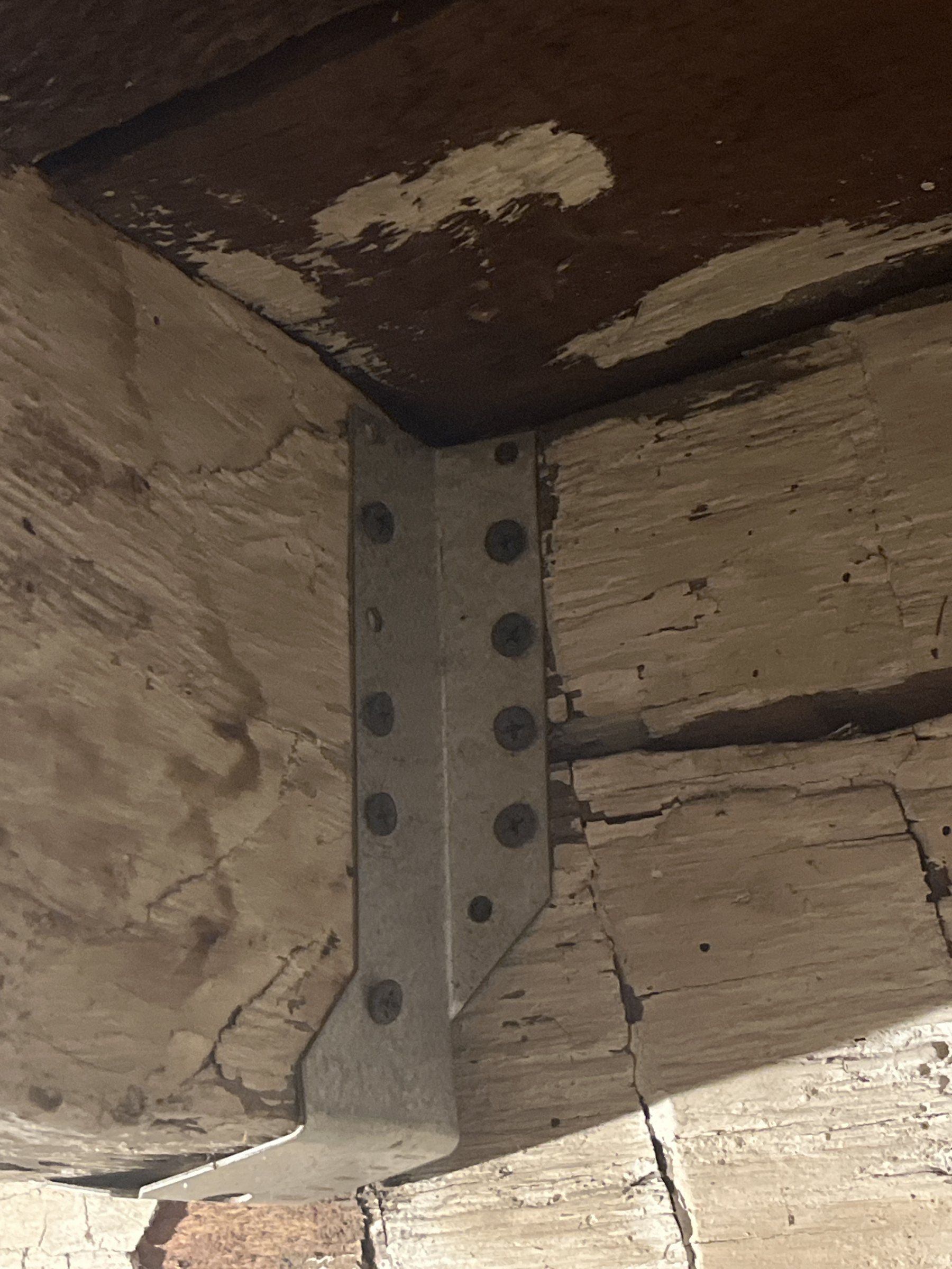 Face-mount joist hanger on a hewn girt with screws in some holes and other holes empty